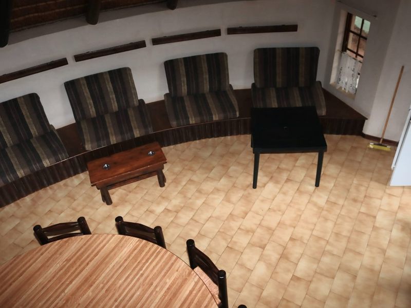 A circular living area featuring built-in bench seating, tiled flooring, and a traditional thatch roof ceiling, offering a unique rustic layout.