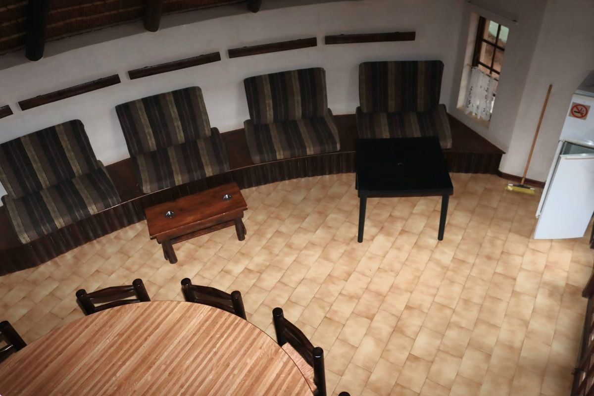 A circular living area featuring built-in bench seating, tiled flooring, and a traditional thatch roof ceiling, offering a unique rustic layout.