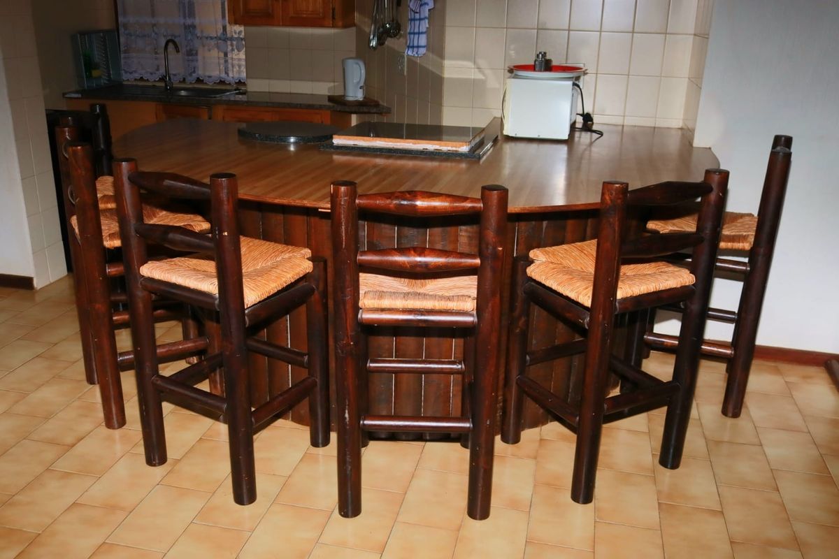 A kitchen area featuring a large built-in breakfast bar with a laminate countertop, tiled backsplash, and ceramic floor tiles.