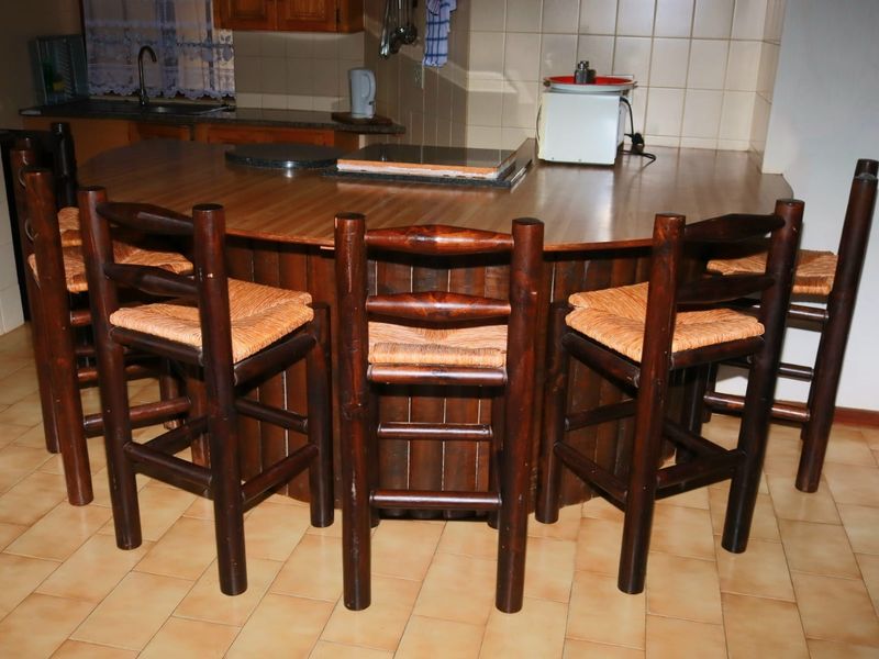 A kitchen area featuring a large built-in breakfast bar with a laminate countertop, tiled backsplash, and ceramic floor tiles.