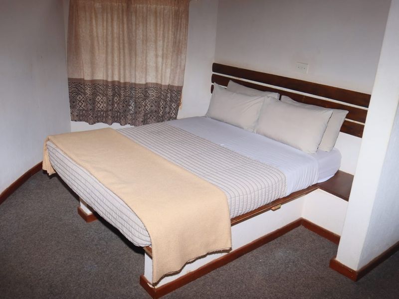 A bedroom featuring a built-in wooden headboard, carpeted flooring, and neutral wall finishes.