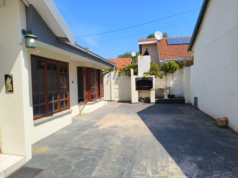 A private rear courtyard featuring a built-in braai, paved flooring, and timber-framed windows, offering a functional outdoor entertainment space.