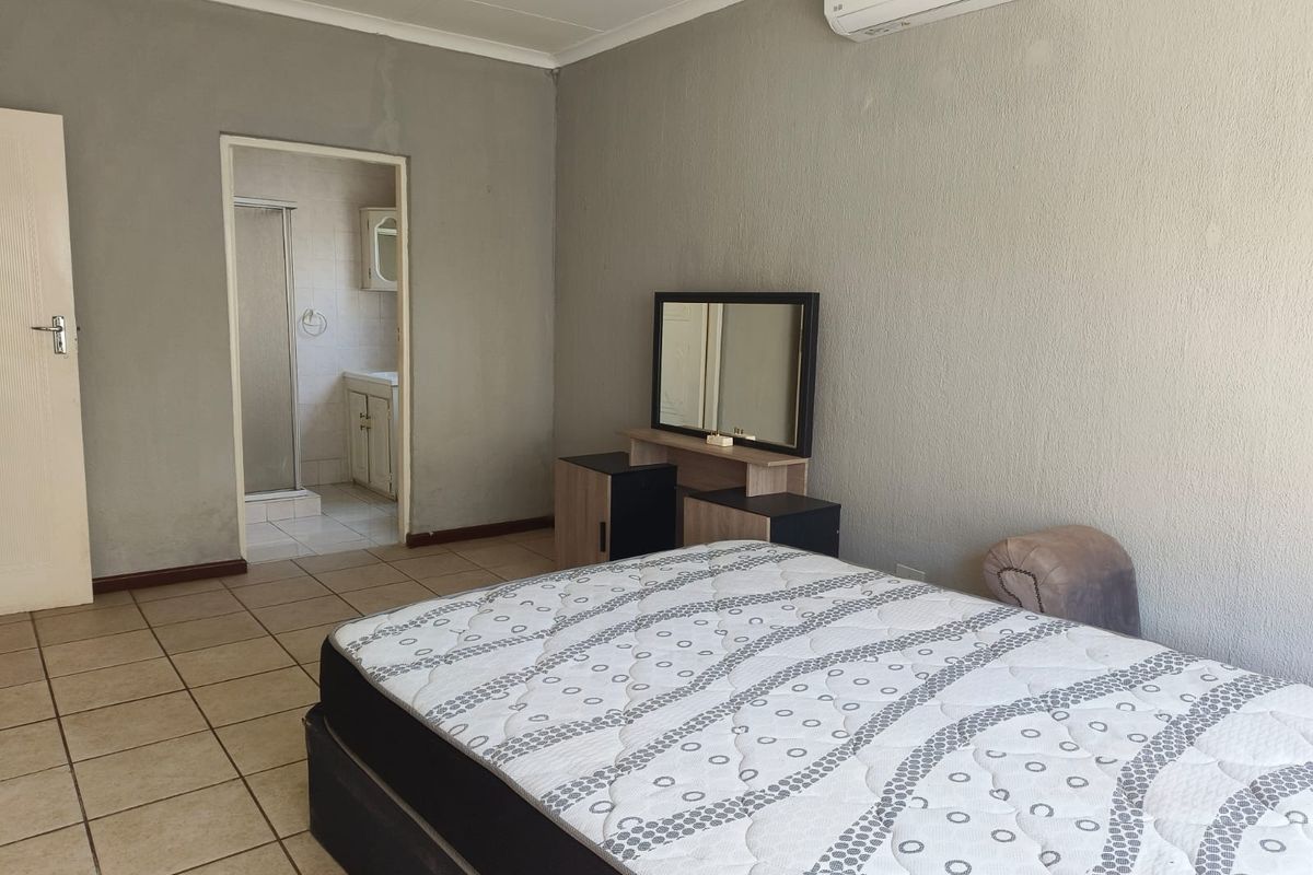 A bedroom featuring tiled flooring, a split-system air conditioner, and direct access to an en-suite bathroom.