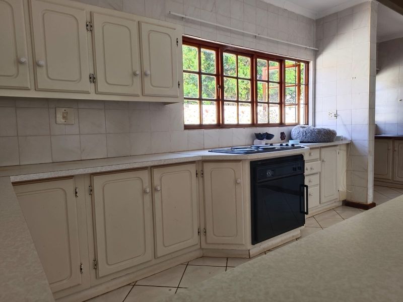 A functional kitchen featuring built-in cabinetry, laminate countertops, a built-in oven, and a hob, with tiled backsplash and flooring throughout.