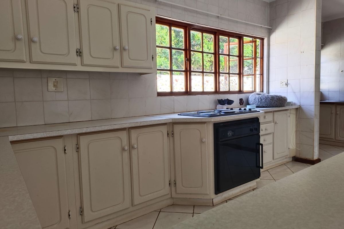 A functional kitchen featuring built-in cabinetry, laminate countertops, a built-in oven, and a hob, with tiled backsplash and flooring throughout.
