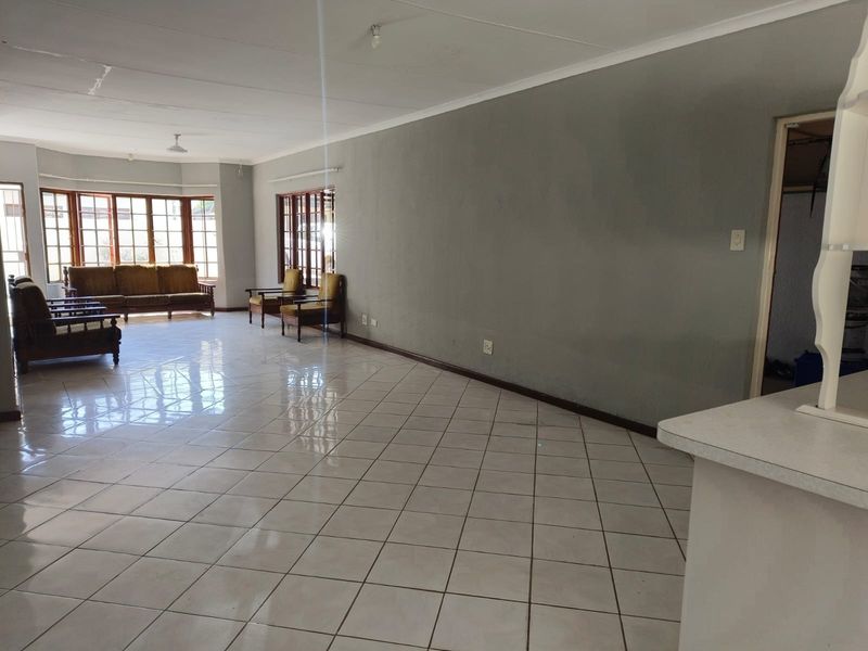 Spacious open-plan living area featuring large bay windows, ceramic tile flooring, and neutral wall finishes, offering a bright and versatile layout.
