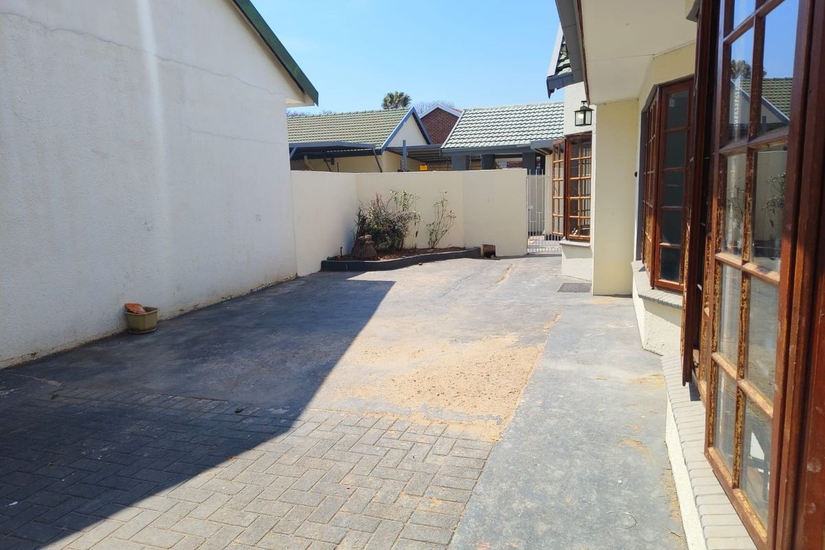 A rear exterior courtyard area featuring paved surfaces, boundary walls, and timber-framed windows, offering potential for landscaping or outdoor living improvements.