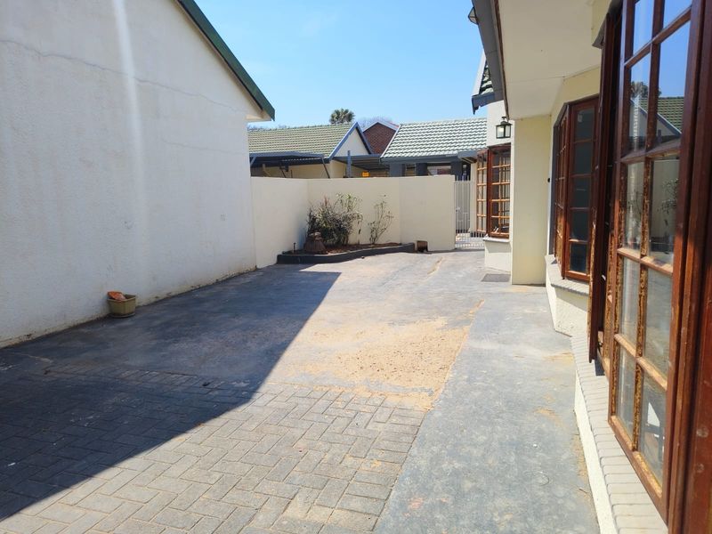 A rear exterior courtyard area featuring paved surfaces, boundary walls, and timber-framed windows, offering potential for landscaping or outdoor living improvements.