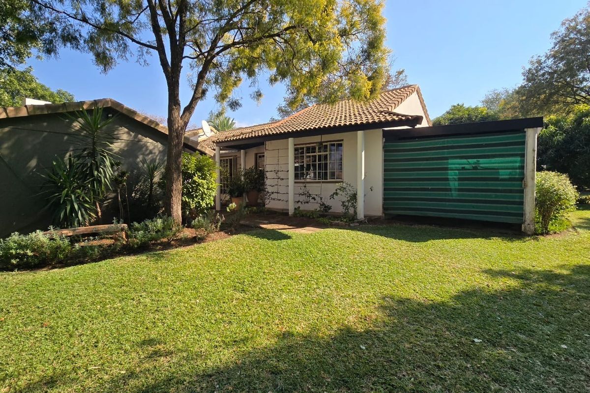 A view of the rear exterior of the retirement unit, featuring a tiled roof, covered patio area, and a well-maintained garden.