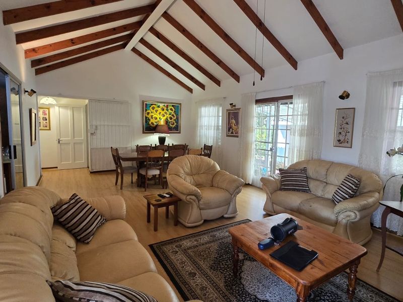 Spacious open-plan living and dining area featuring a high vaulted ceiling with exposed timber beams and direct access to the outdoor patio.