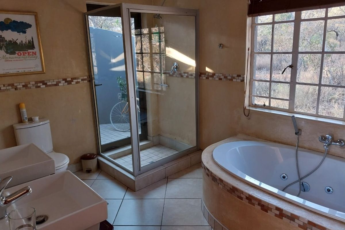 Bathroom featuring a built-in bathtub, separate shower enclosure, dual vanity sinks, and tiled flooring with a mosaic accent border.