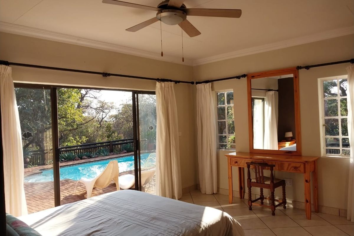 Spacious bedroom featuring tiled floors, a ceiling fan, and large sliding glass doors providing direct access to the outdoor pool area.