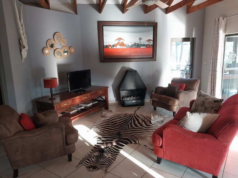 A cozy living room featuring exposed timber rafters, tiled flooring, and a built-in fireplace, creating a warm and inviting atmosphere.