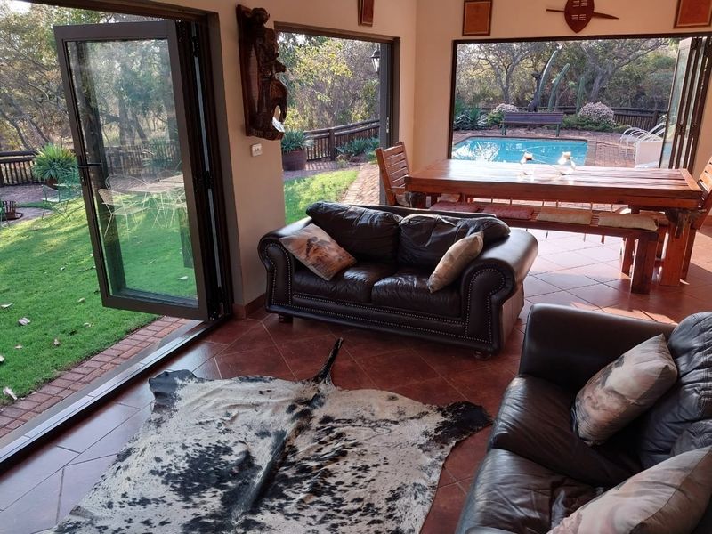 Spacious living area featuring terracotta floor tiles and large bi-fold doors that open directly onto the outdoor patio and pool area.