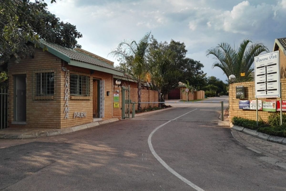 Entrance view of Panorama Park residential estate featuring a brick security gatehouse, boom gate access control, and paved road infrastructure.