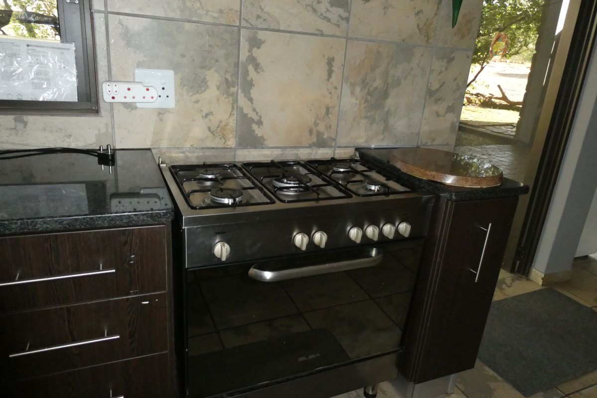A functional kitchen area featuring a built-in gas stove and oven, dark cabinetry, and stone tile backsplash with granite countertops.