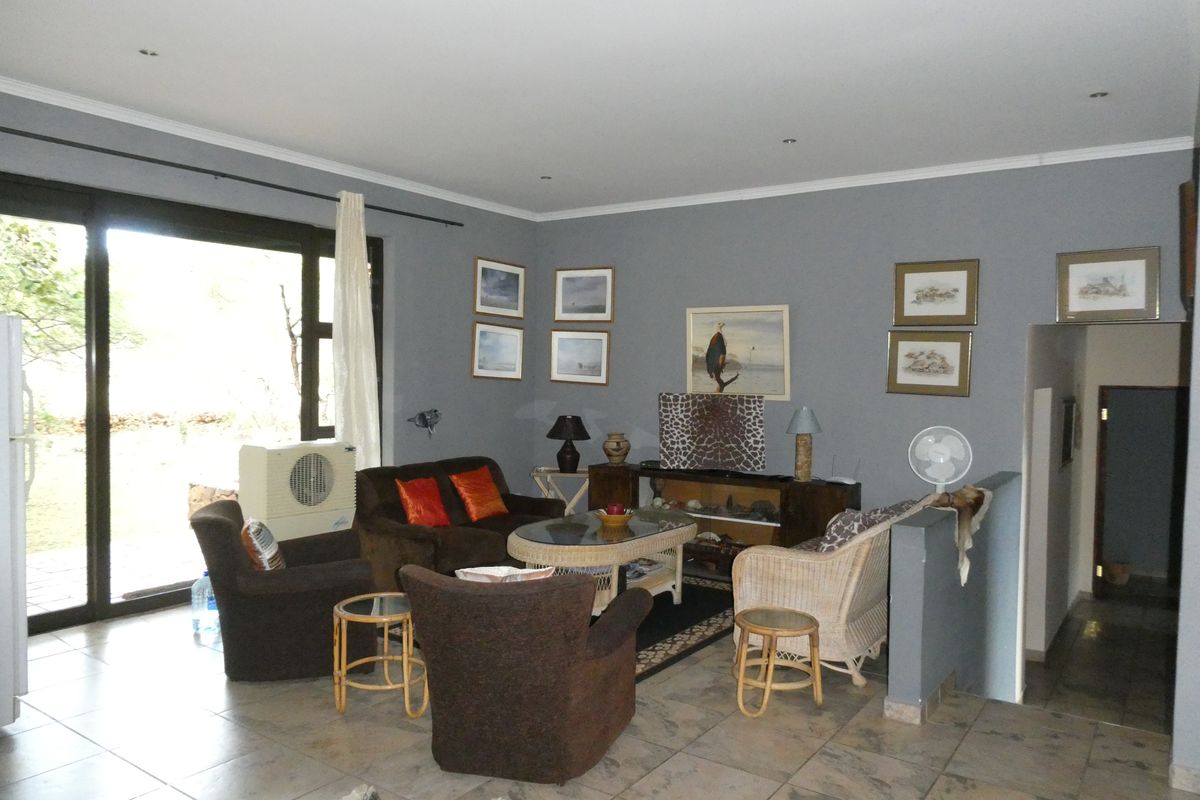 A spacious living room featuring tiled flooring, recessed downlighting, and a large sliding glass door providing access to the exterior.
