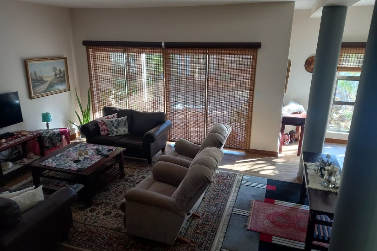 A spacious living area featuring large sliding glass doors with bamboo blinds, recessed ceiling lighting, and structural support columns.