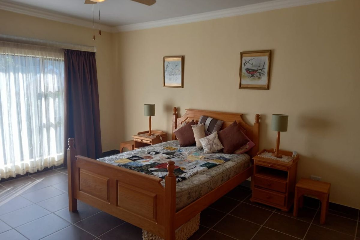A bedroom featuring tiled flooring, a ceiling fan, and sliding glass doors providing access to the exterior.