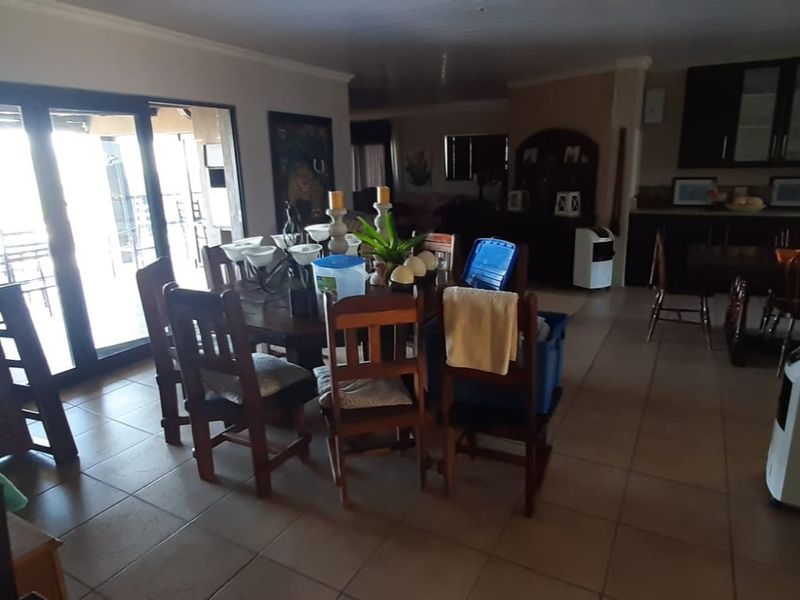 Spacious open-plan living and dining area featuring tiled flooring, coved ceilings, and direct access to an outdoor patio through sliding glass doors.