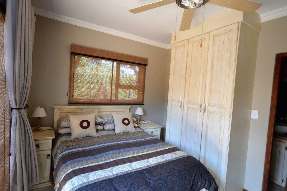 A cozy bedroom featuring a built-in wardrobe, ceiling fan, and neutral wall tones, offering a functional and comfortable living space.