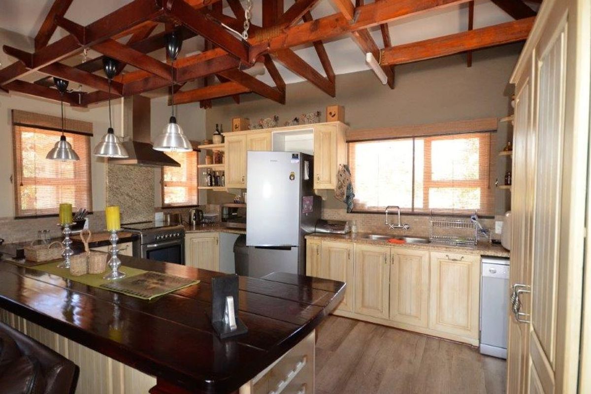 Spacious kitchen featuring exposed timber roof trusses, a large central island, ample cabinetry, and modern stainless steel fixtures.