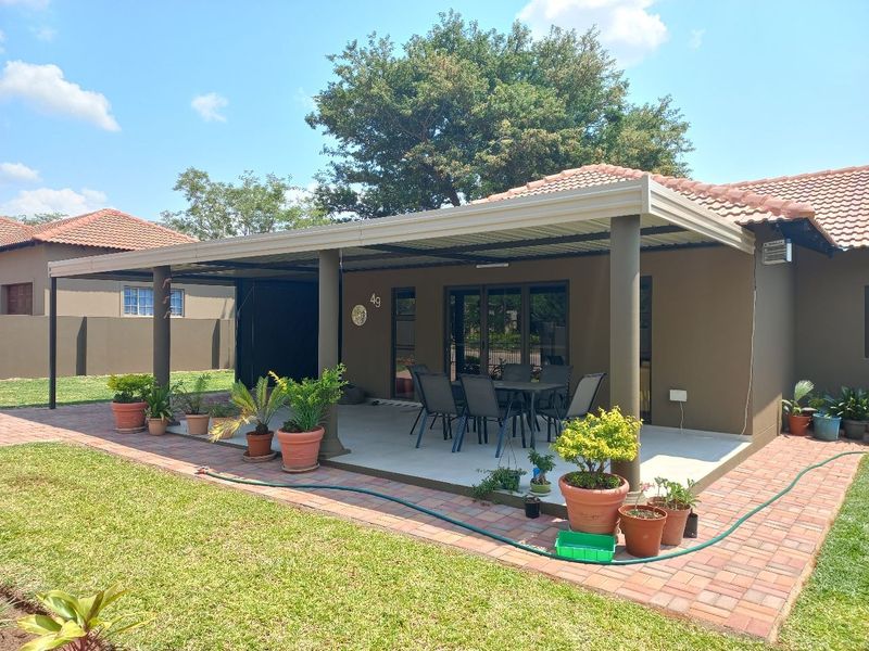 A well-maintained covered patio area featuring paved flooring, sturdy support columns, and direct access to the home through sliding glass doors.