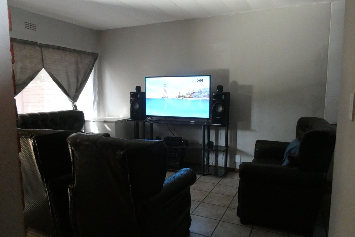 A living room featuring tiled flooring and a ceiling with integrated ventilation, providing a functional space for relaxation.