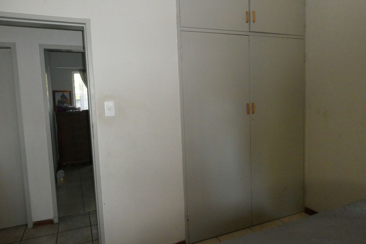 A bedroom featuring built-in floor-to-ceiling cupboards with overhead storage and a doorway leading to an adjacent room.