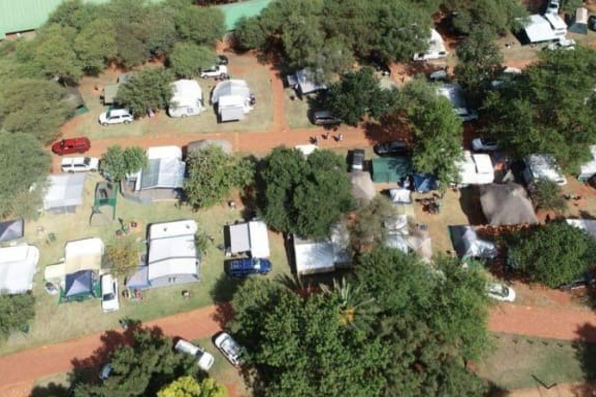 Aerial view of the lodge grounds featuring multiple camping and caravan sites nestled among mature trees and internal access paths.