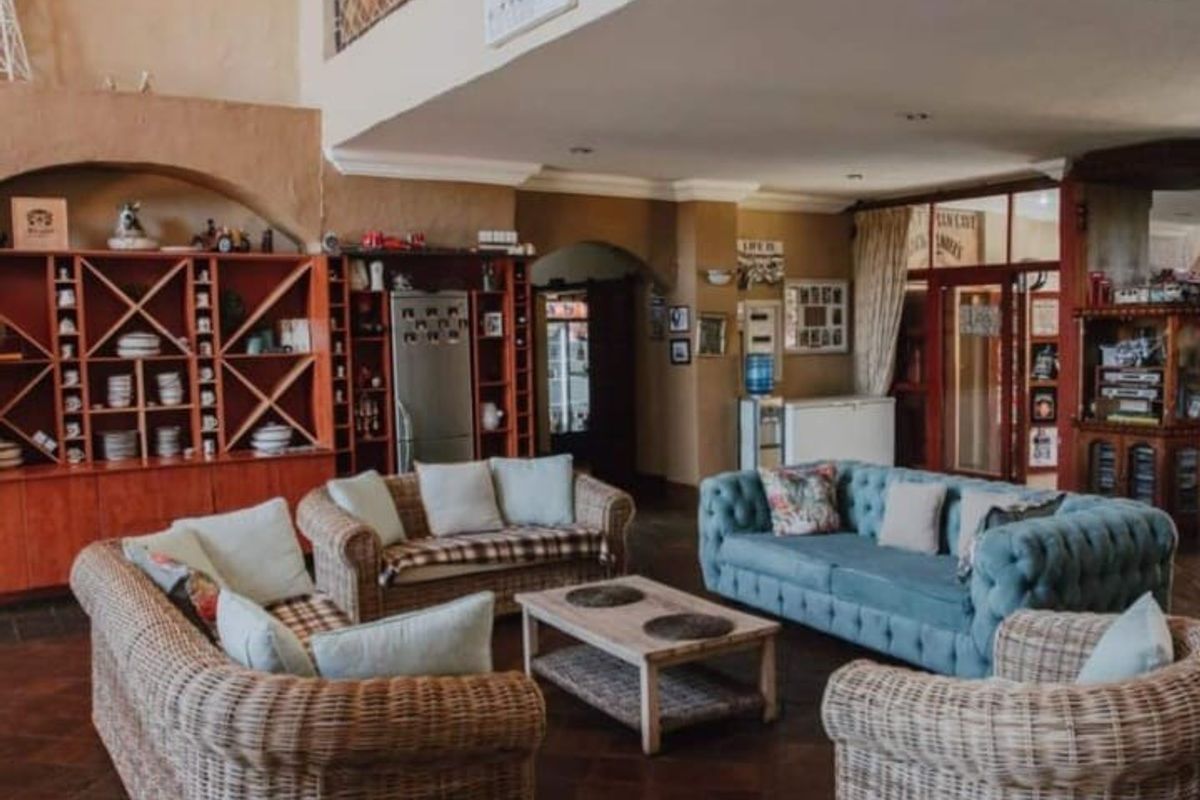 Spacious living area featuring built-in wooden shelving, arched architectural details, and tiled flooring, offering a warm and inviting atmosphere.
