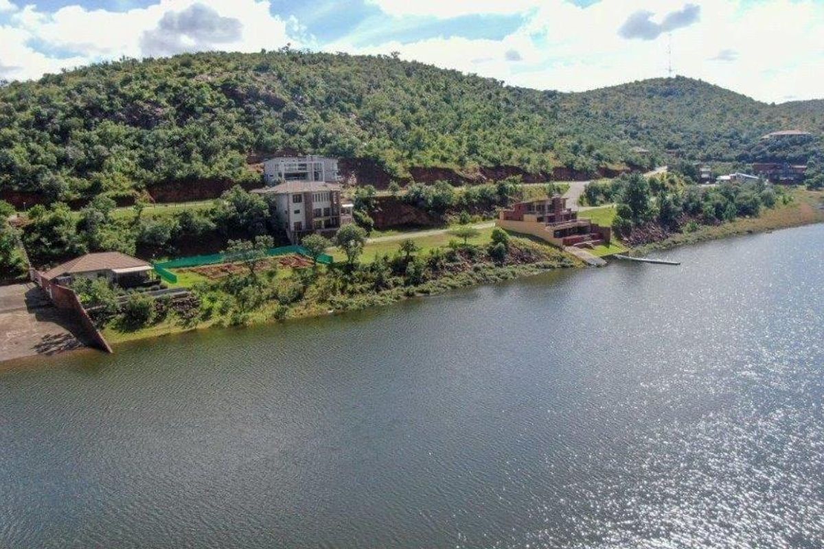 Aerial view of the residential waterfront property featuring direct water access, a boat ramp, and established landscaping along the shoreline.