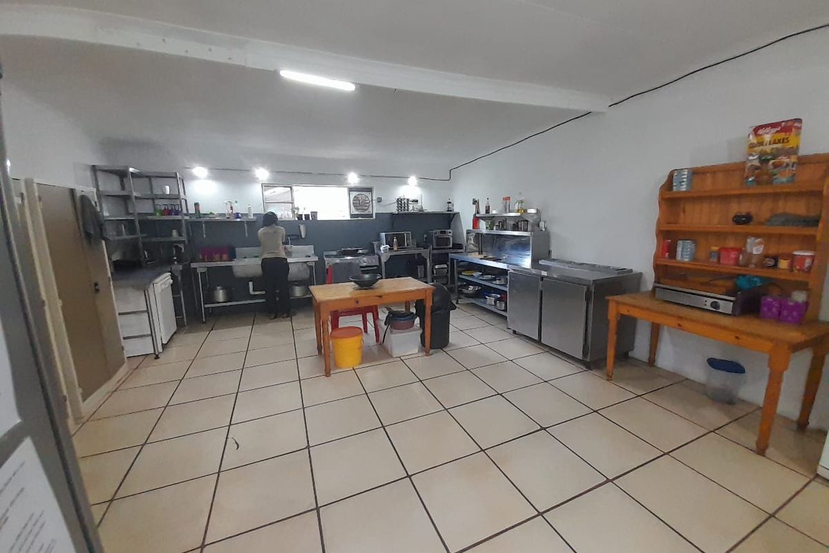A functional commercial-style kitchen featuring stainless steel prep counters, industrial sinks, and tiled flooring, suitable for high-volume food preparation.