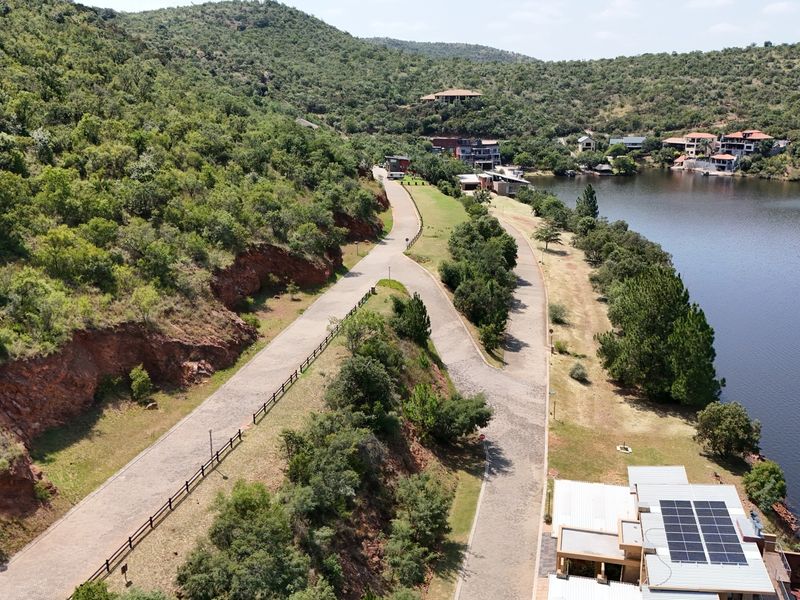 Aerial view of the residential estate featuring paved access roads, post and rail fencing, and scenic lake frontage with surrounding natural landscape.