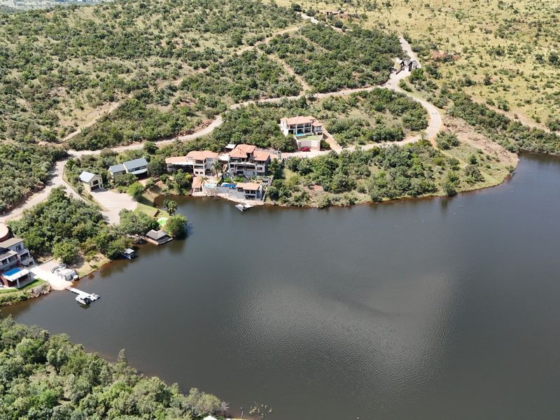 Aerial view of a residential estate featuring multiple waterfront properties, private jetties, and established access roads set within a natural landscape.