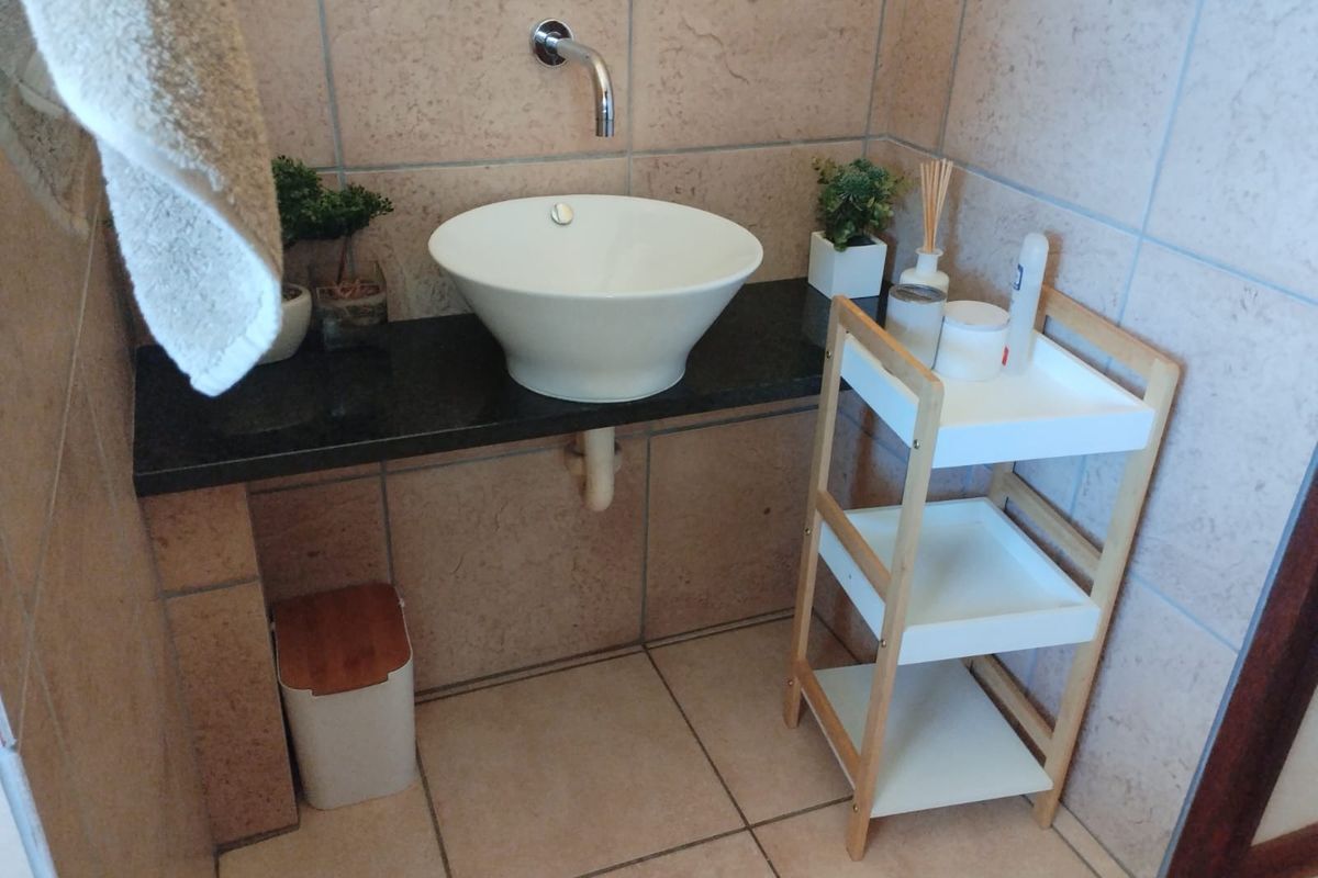A bathroom vanity area featuring a modern vessel sink mounted on a dark stone countertop with tiled walls and flooring.