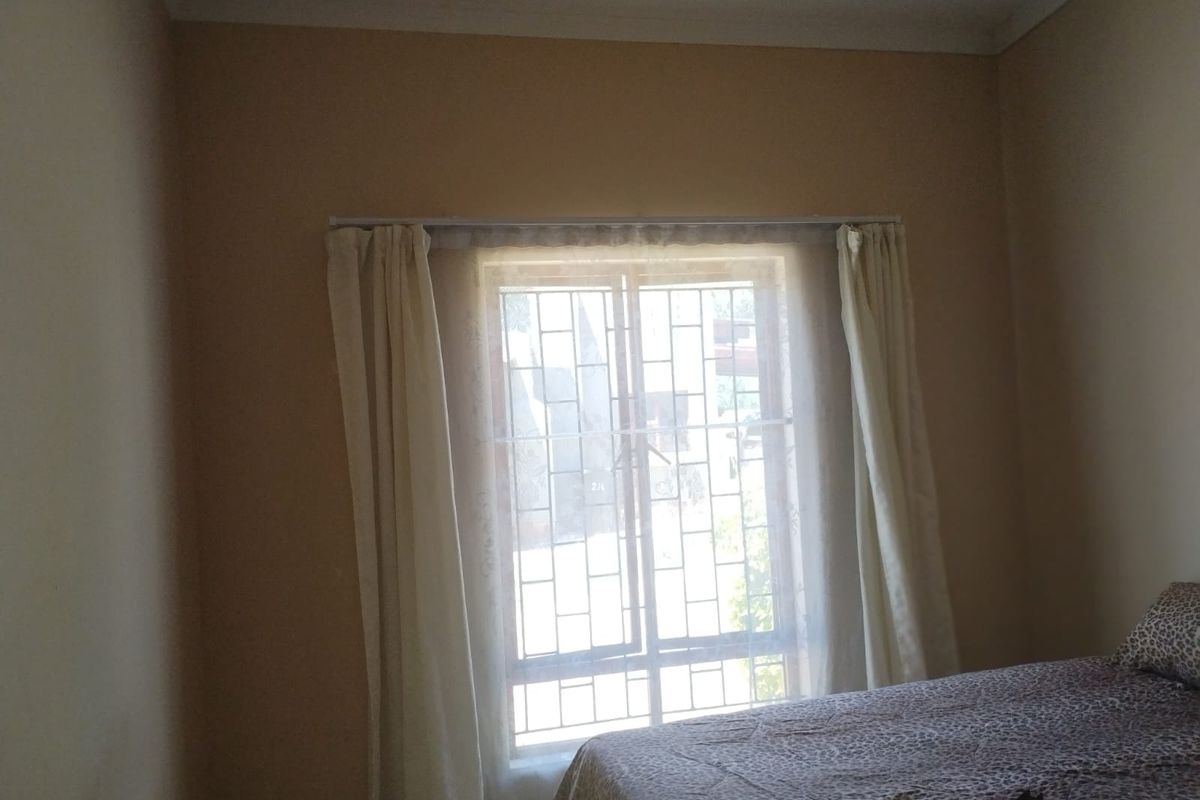 A bedroom featuring a window with fitted security bars and curtain rails.