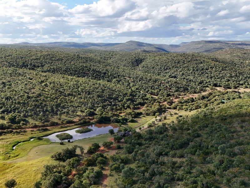 Aerial view of a large residential vacant land plot featuring a natural dam, rolling hills, and extensive indigenous vegetation.
