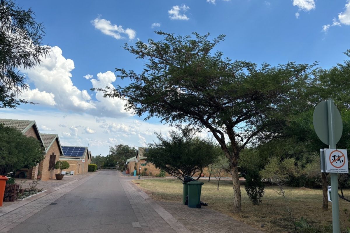 A view of a residential street featuring paved roads, sidewalks, and houses with solar panels under a clear blue sky.