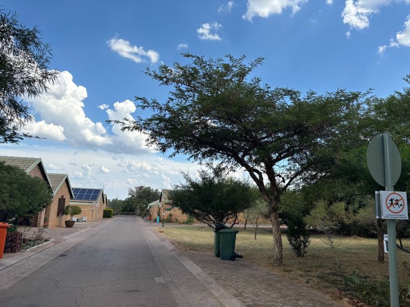 A view of a residential street featuring paved roads, sidewalks, and houses with solar panels under a clear blue sky.