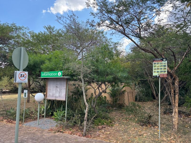 A landscaped garden area featuring a brick wall, paved walkway, and informational signage within a residential estate setting.
