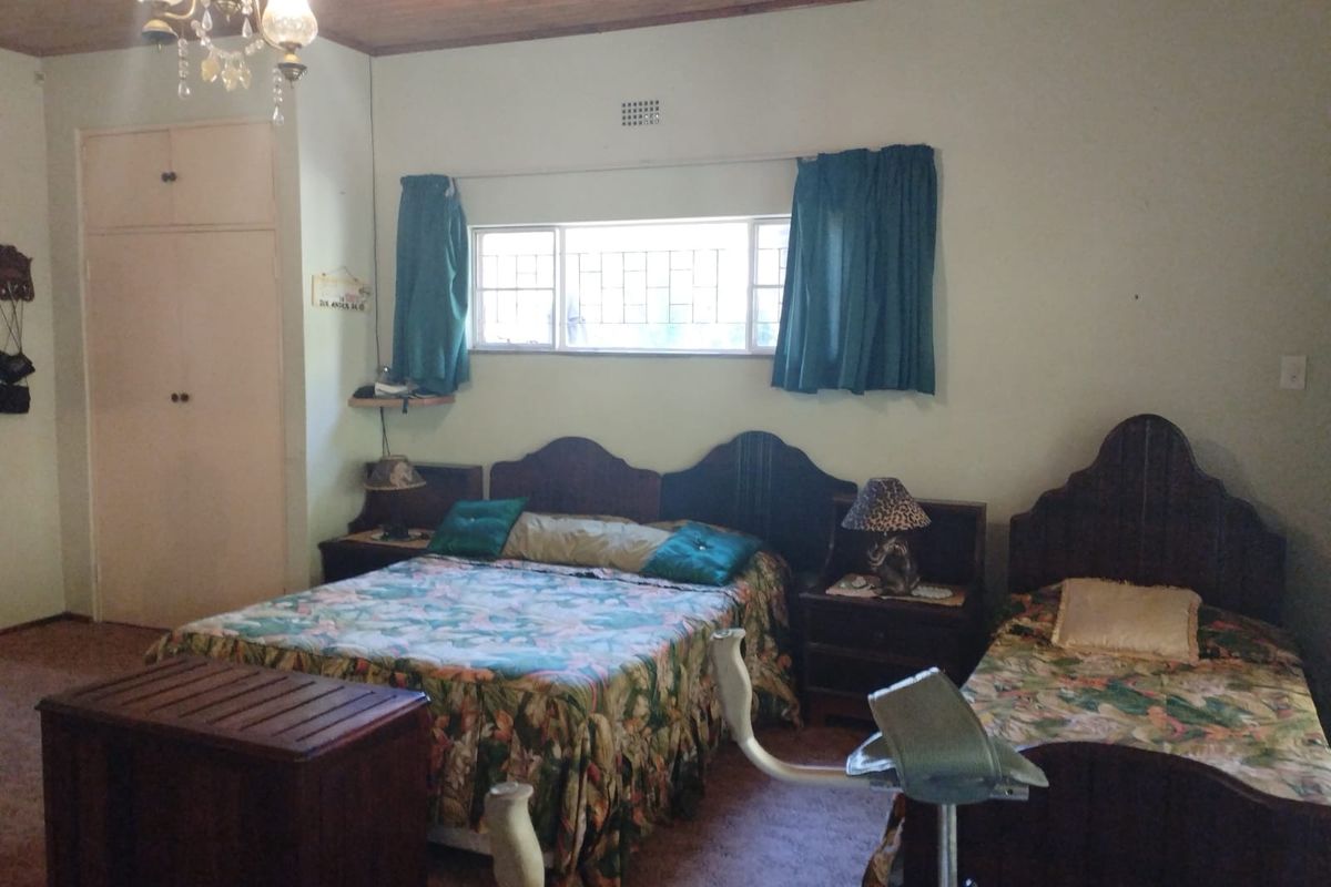 A spacious bedroom featuring built-in cupboards, a timber-paneled ceiling, and security bars on the windows.