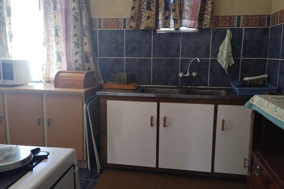A functional kitchen area featuring built-in cabinetry, a double basin sink with mixer tap, and tiled wall splashbacks.