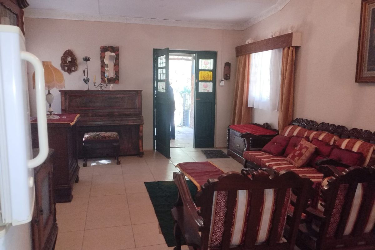 A living room area featuring tiled flooring, a built-in doorway leading to an exterior space, and traditional interior finishes.