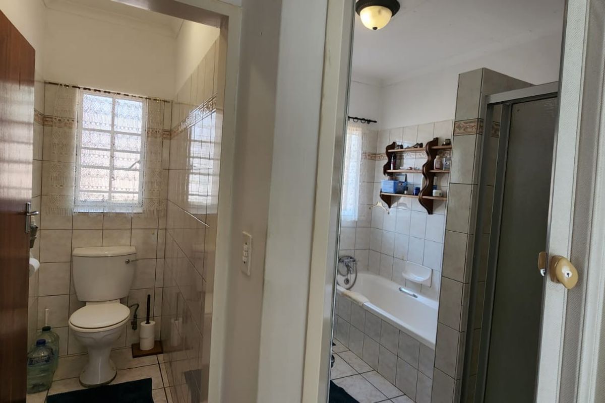 A functional bathroom featuring a bathtub, separate shower enclosure, and toilet with tiled walls and flooring.