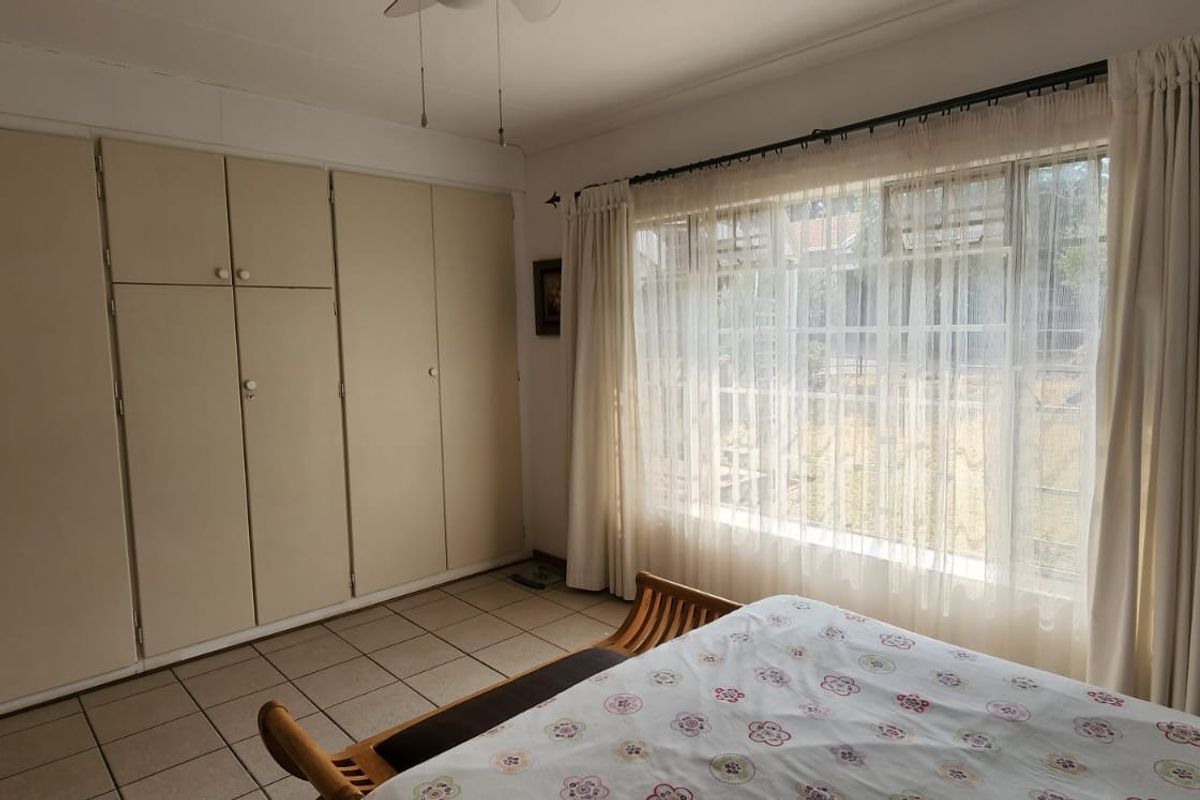 A bedroom featuring built-in floor-to-ceiling cabinetry and large windows with security bars, providing natural light and ample storage space.