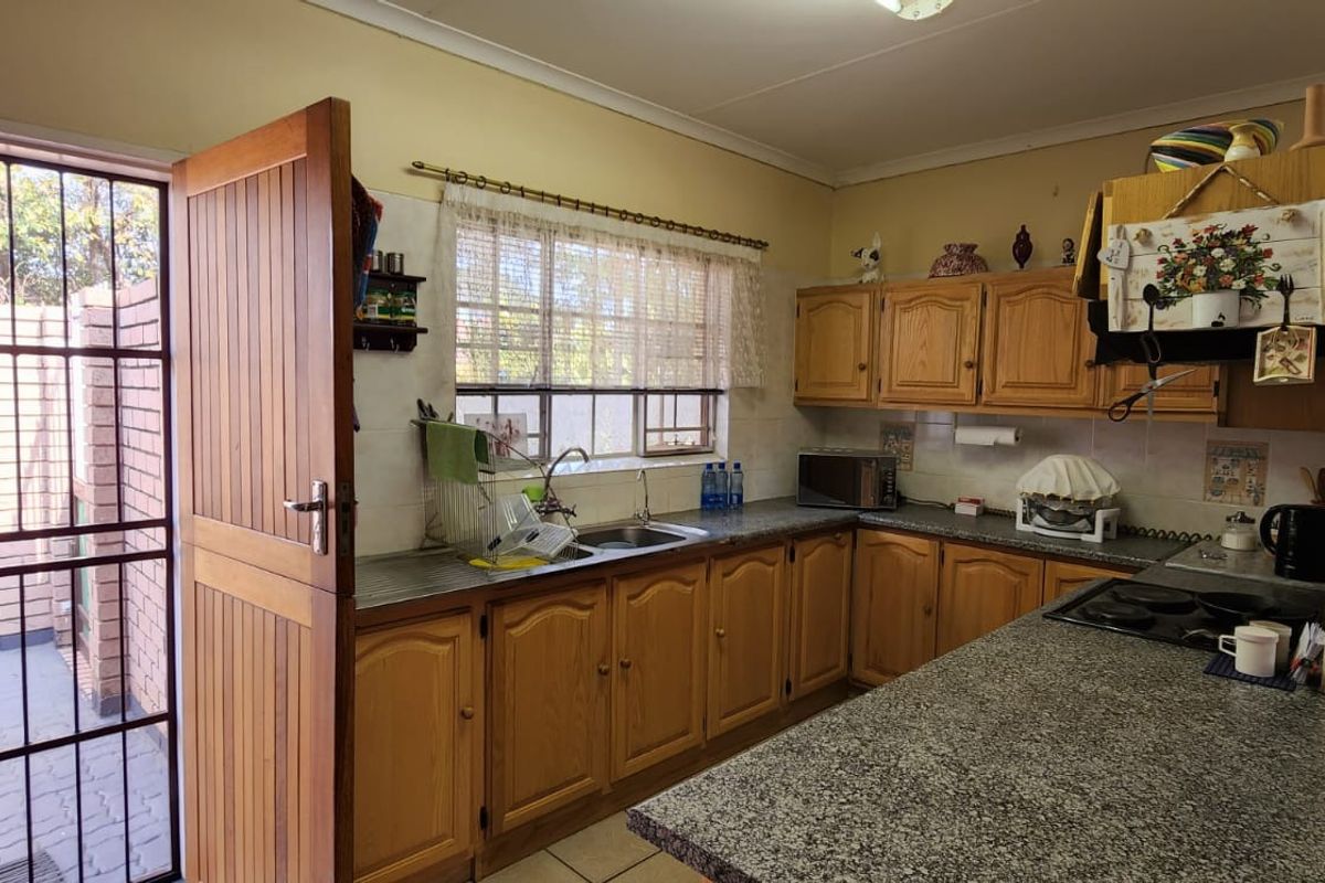 A functional kitchen featuring wooden cabinetry, granite-look countertops, a built-in hob, and direct access to an enclosed outdoor courtyard area.