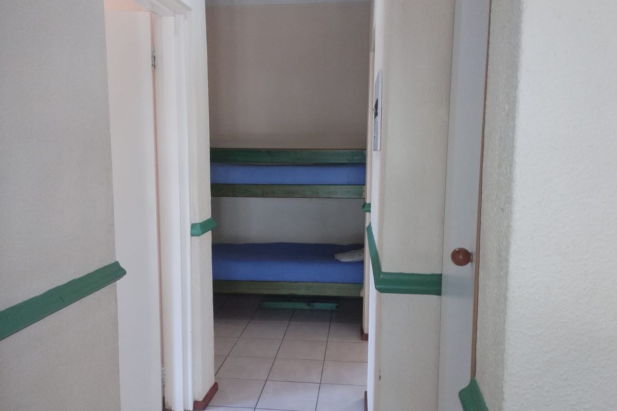 A view through a hallway into a small bedroom featuring tiled flooring and green-painted chair rail detailing.