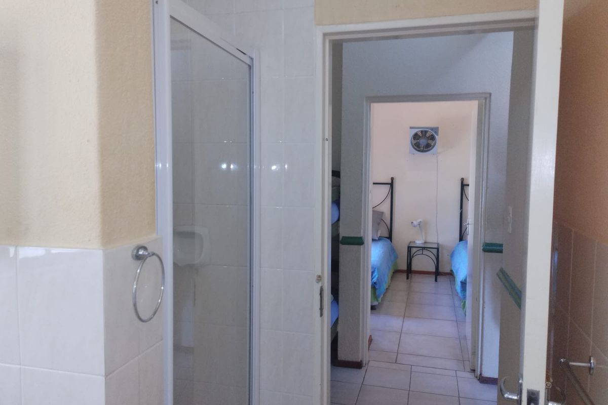A view from a bathroom looking through a doorway into an adjacent bedroom with tiled flooring.