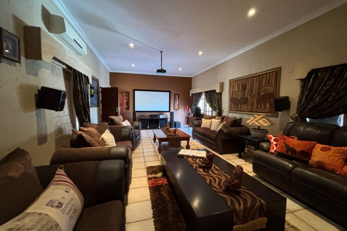 Spacious living area featuring tiled flooring, recessed ceiling lighting, and a dedicated projection screen setup, ideal for a home cinema or entertainment space.